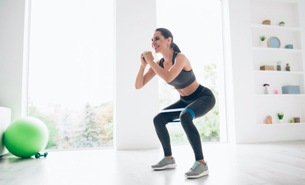Squats dengan elastik pada kaki untuk punggung. Kesan otot mana yang berfungsi